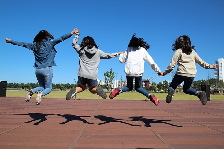 Four girls jumping holding hands